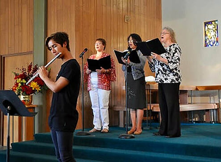 Singers and a flutist leading music at the front of the St. Mark's sanctuary during worship