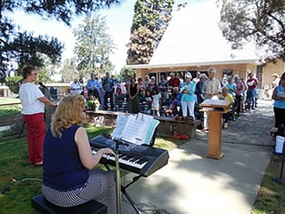 A keyboard player leading music for the congregation gathered outdoors on the church campus