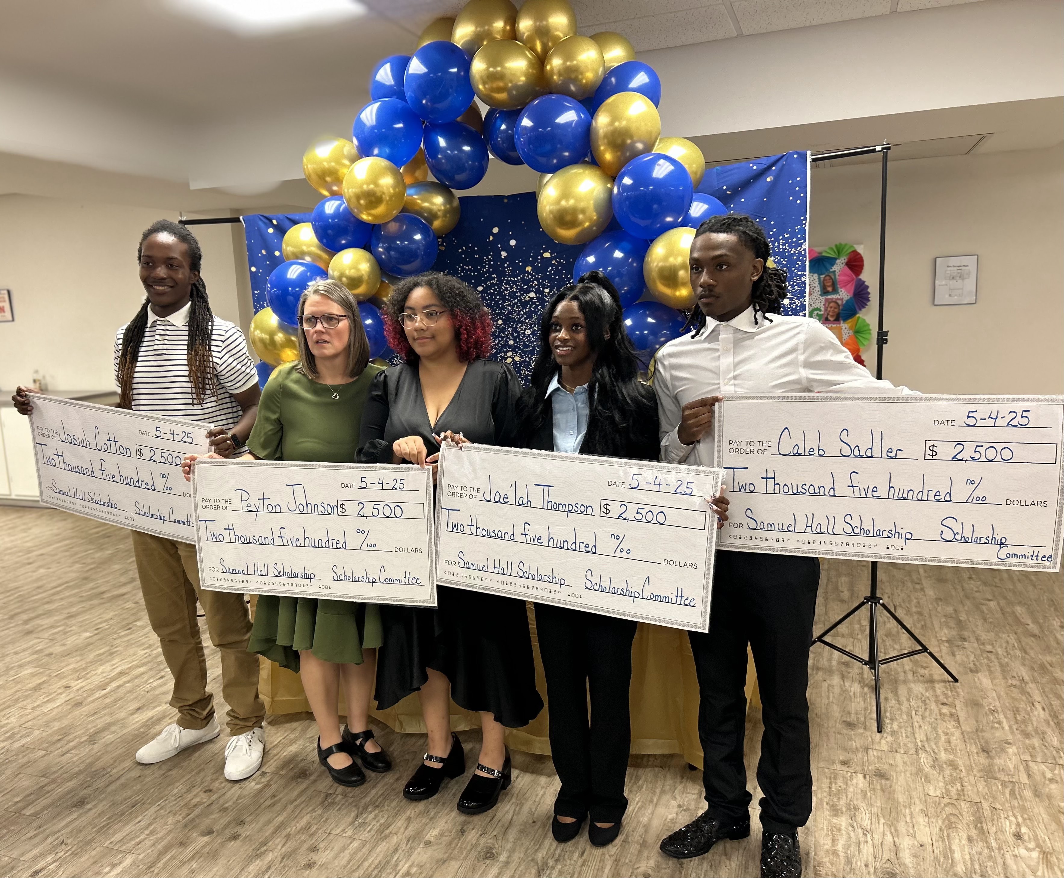 All four 2025 Samuel Hall Scholarship recipients holding their $2,500 checks